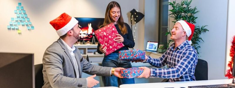 Collega’s wisselen kerstcadeaus uit tijdens een feestelijk moment op kantoor